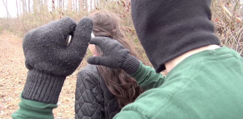 Screenshot from "The Masked Killer" : A man with a mask and gloves is closing in on a girl with her back turned. The man is holding a knife high reaching his other hand out to grab the girl.